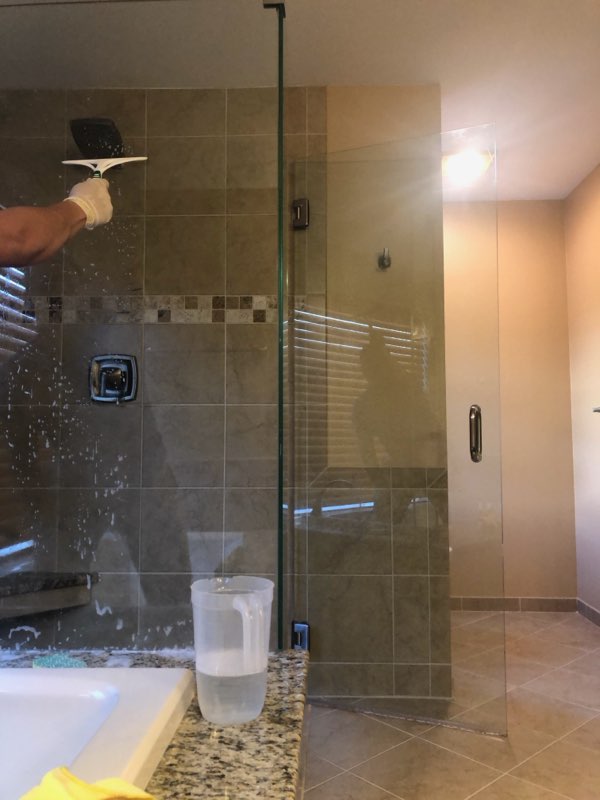 Cleaning a glass shower door in a tiled bathroom